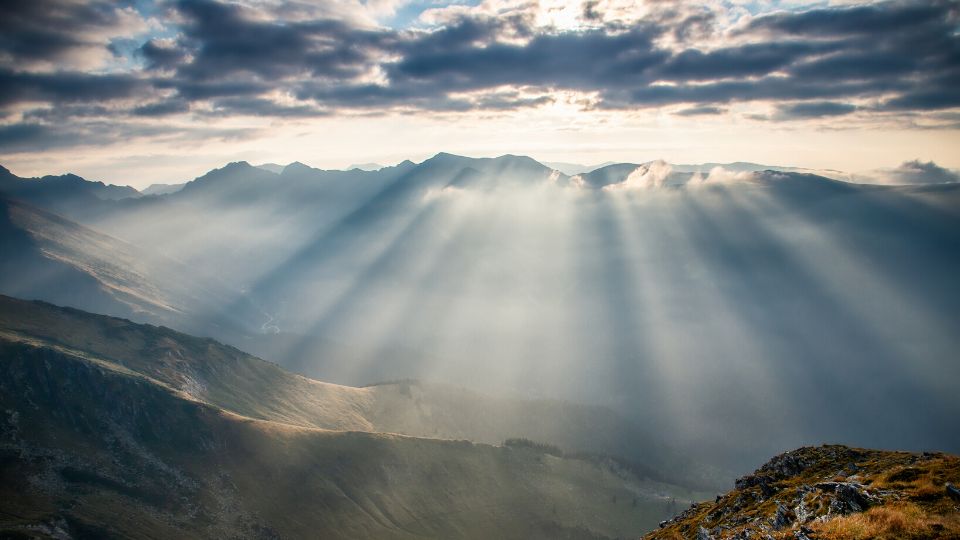 Image of sun rays shining onto mountain through clouds