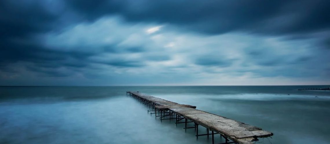 Broken pier fading into dark cloudy horizon